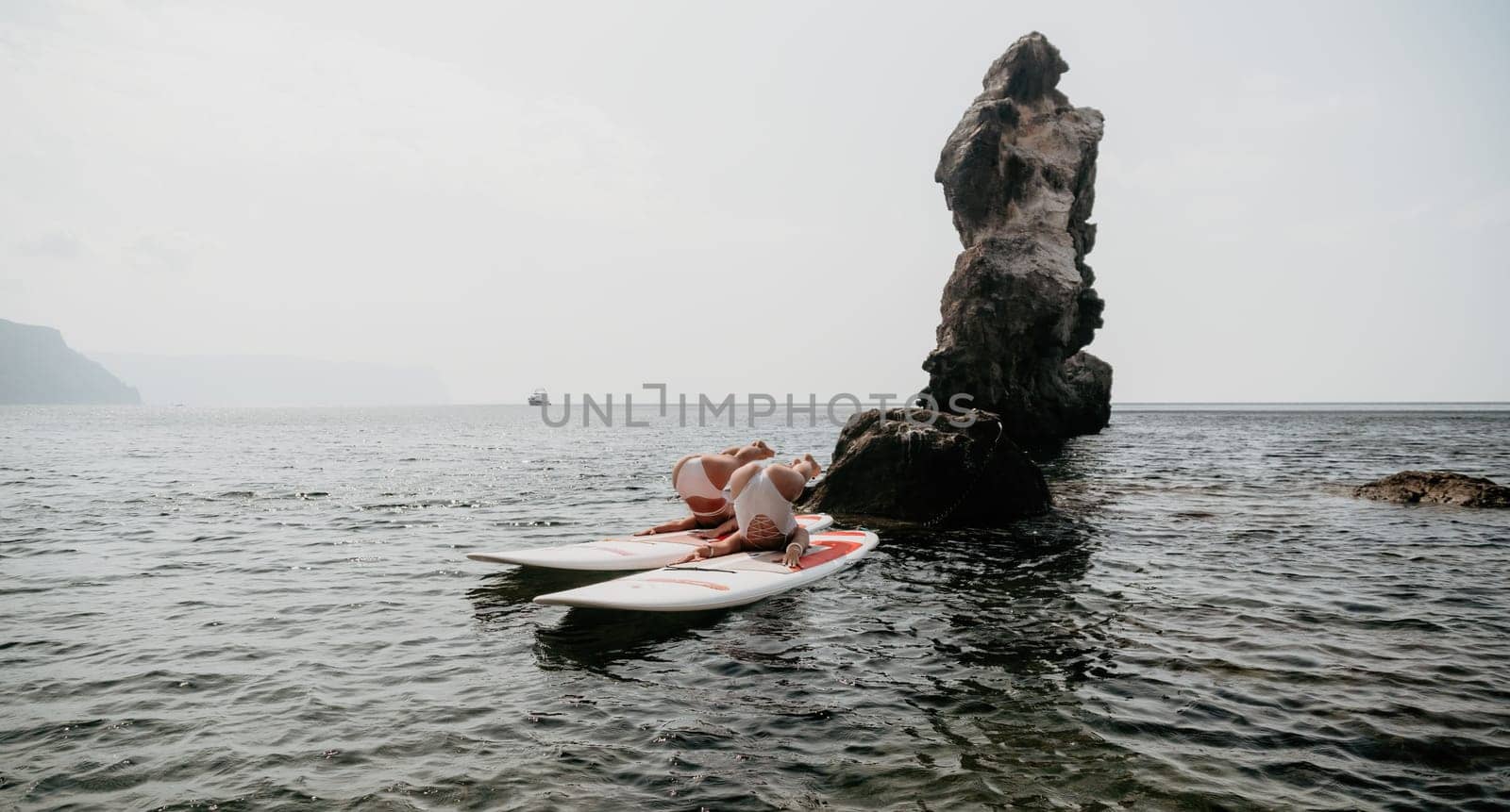 Woman sup yoga. Middle age sporty woman practising yoga pilates on paddle sup surfboard. Female stretching doing workout on sea water. Modern individual hipster outdoor summer sport activity