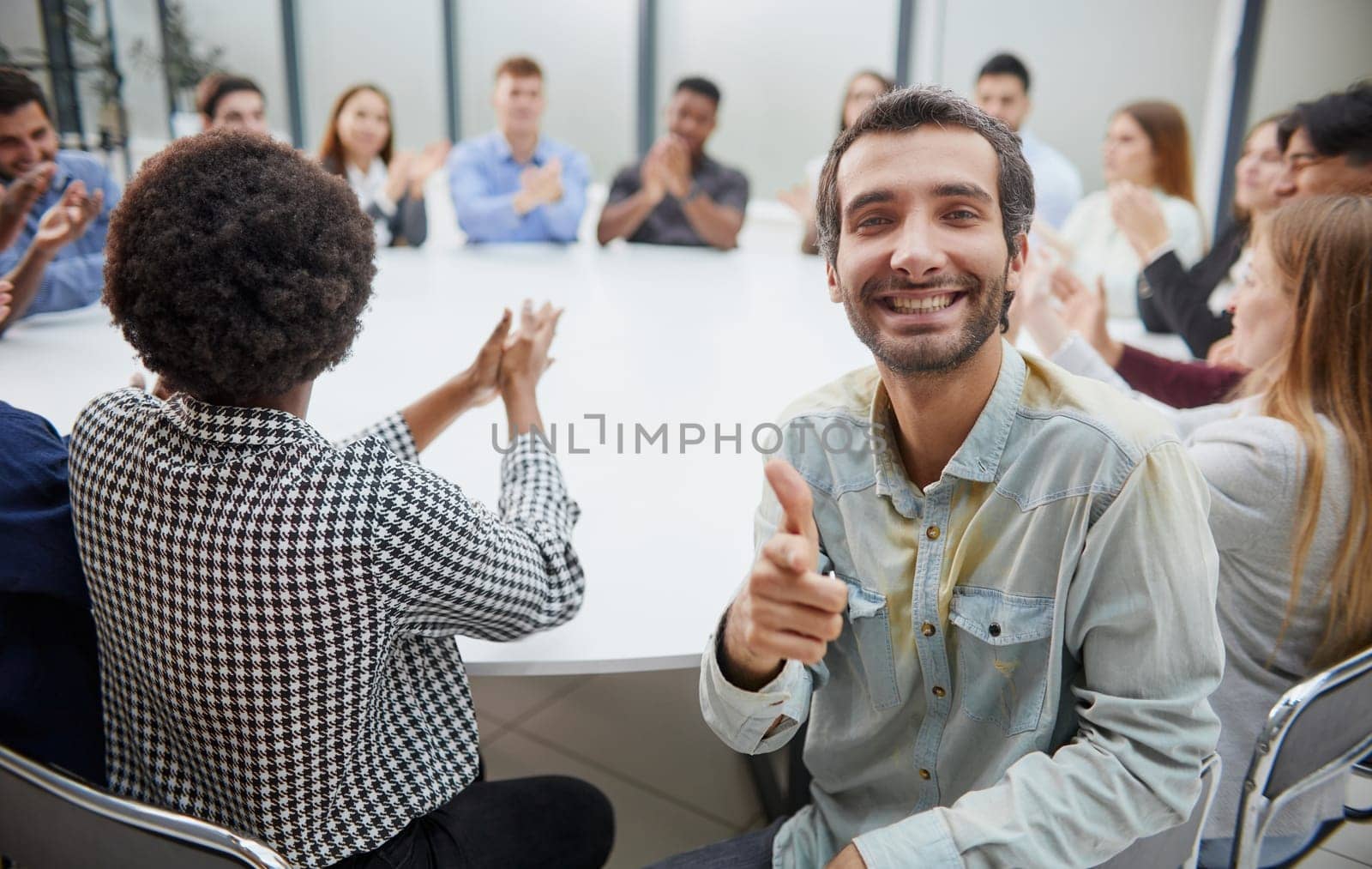 Smiling business group of office workers, executive board members or employees looking at camera sitting at conference table