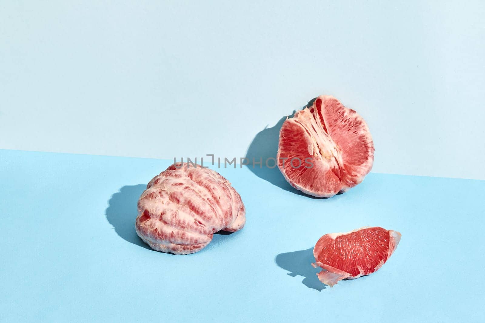 Composition of fresh fruits, juicy grapefruit cutted into slices on blue background. Mock up, two-colored pastel