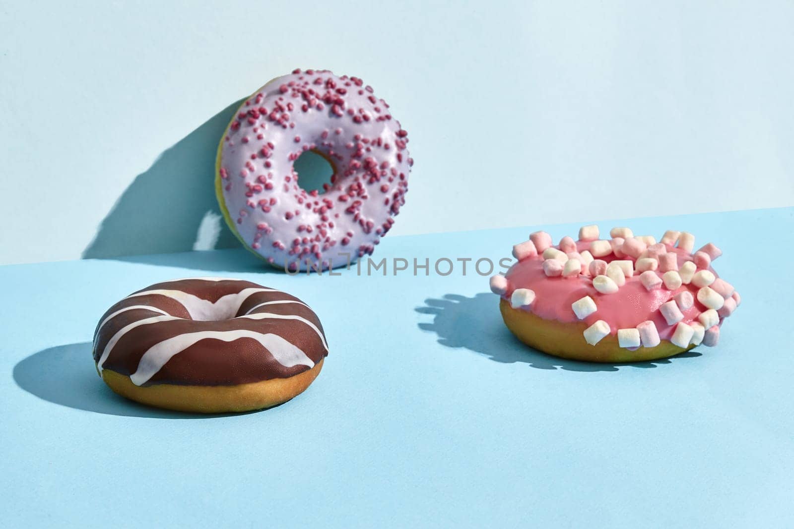 Three sweet tasty donuts in caramel and chocolate icing, on a two-color background by nazarovsergey
