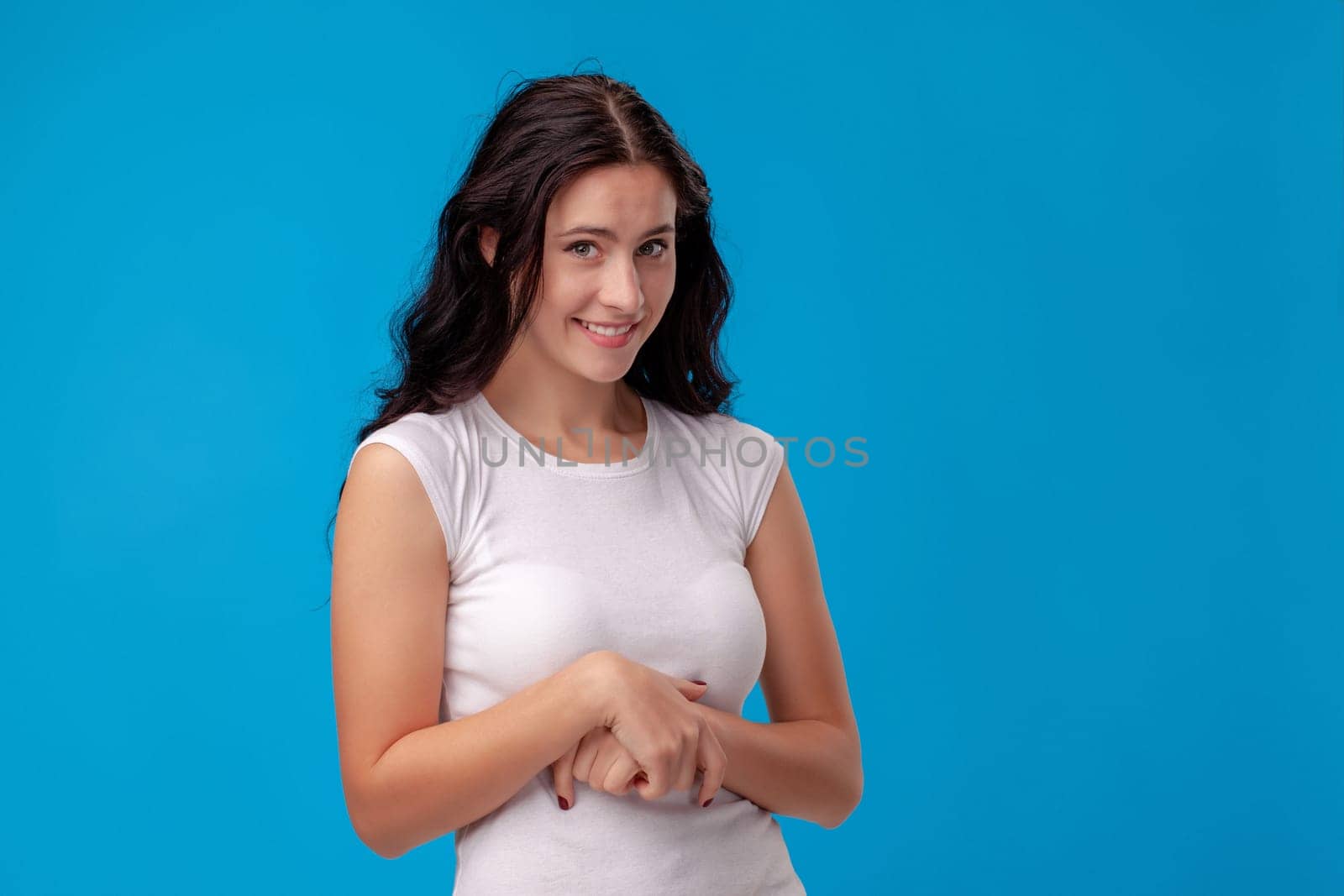 Smiling attractive young woman folds arms on the blue background