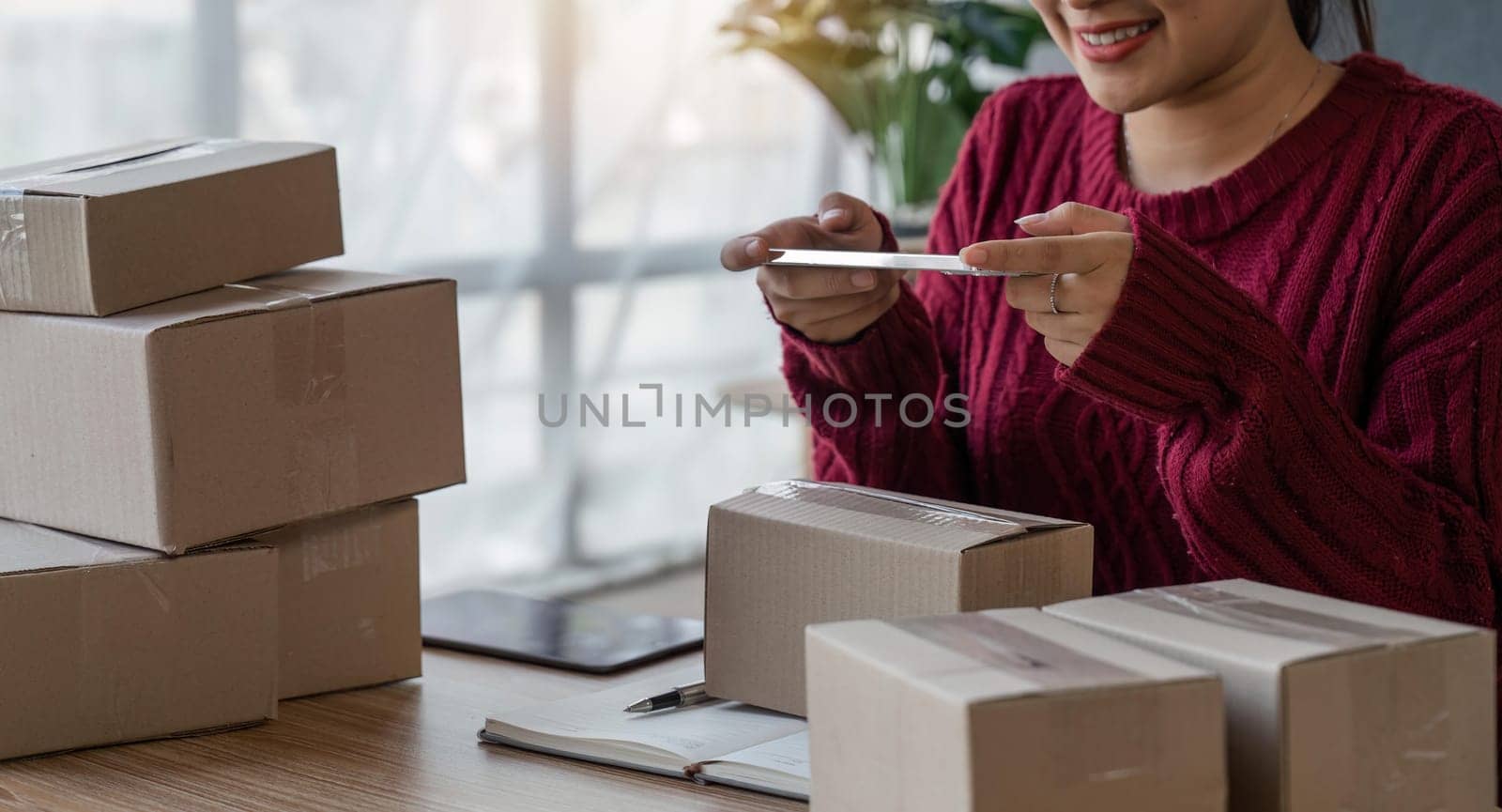 Young women taking photo to packaging with cell telephone for post to sell online on the Internet and preparing pack product box. Selling online ideas concept.