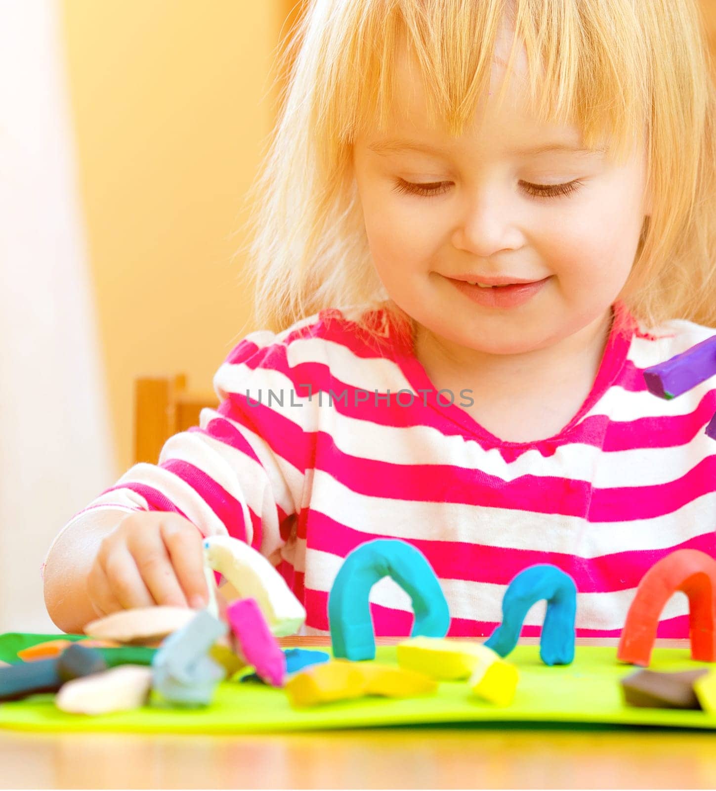 Cute girl playing with plasticine at home