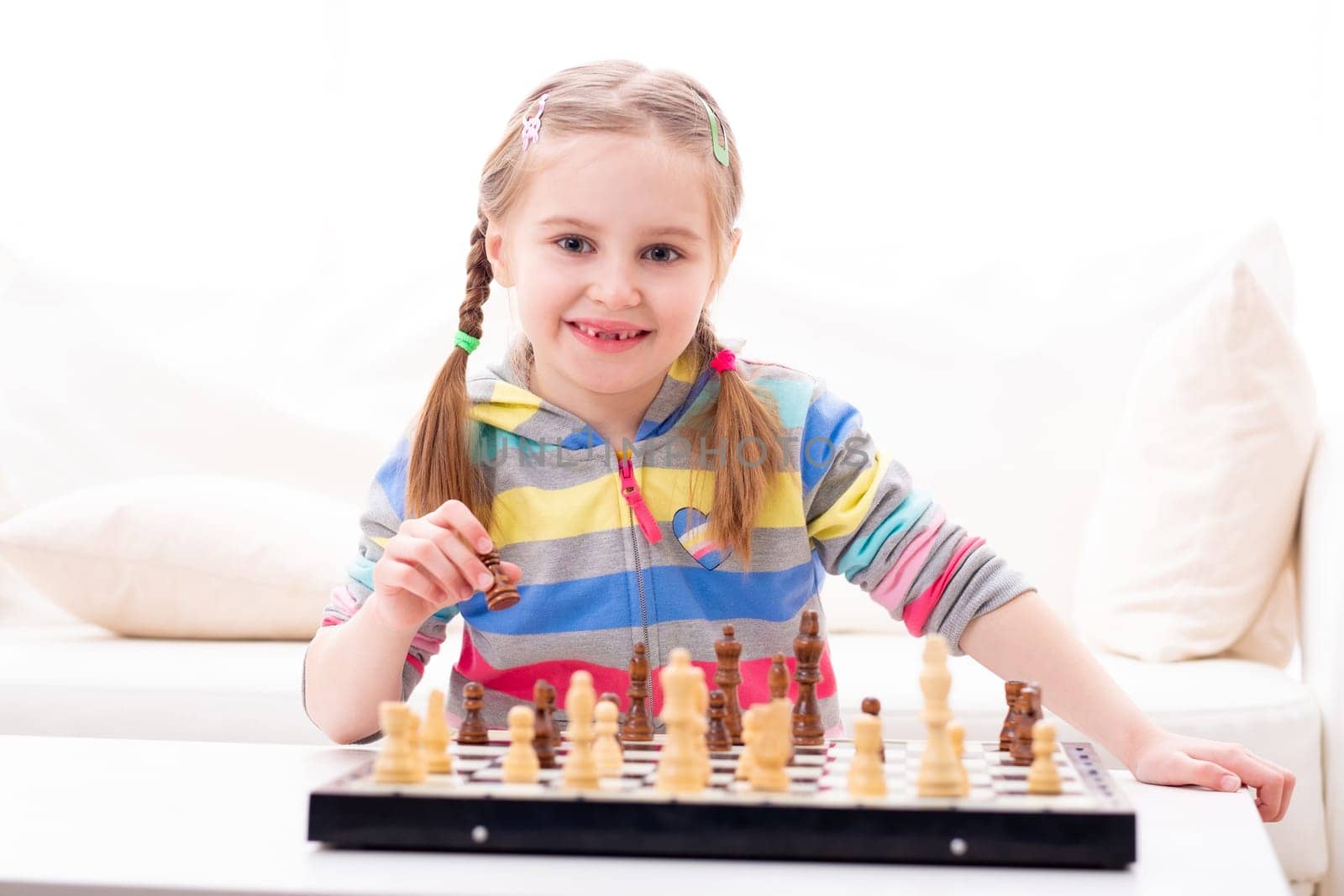 Cute little girl playing chess at home