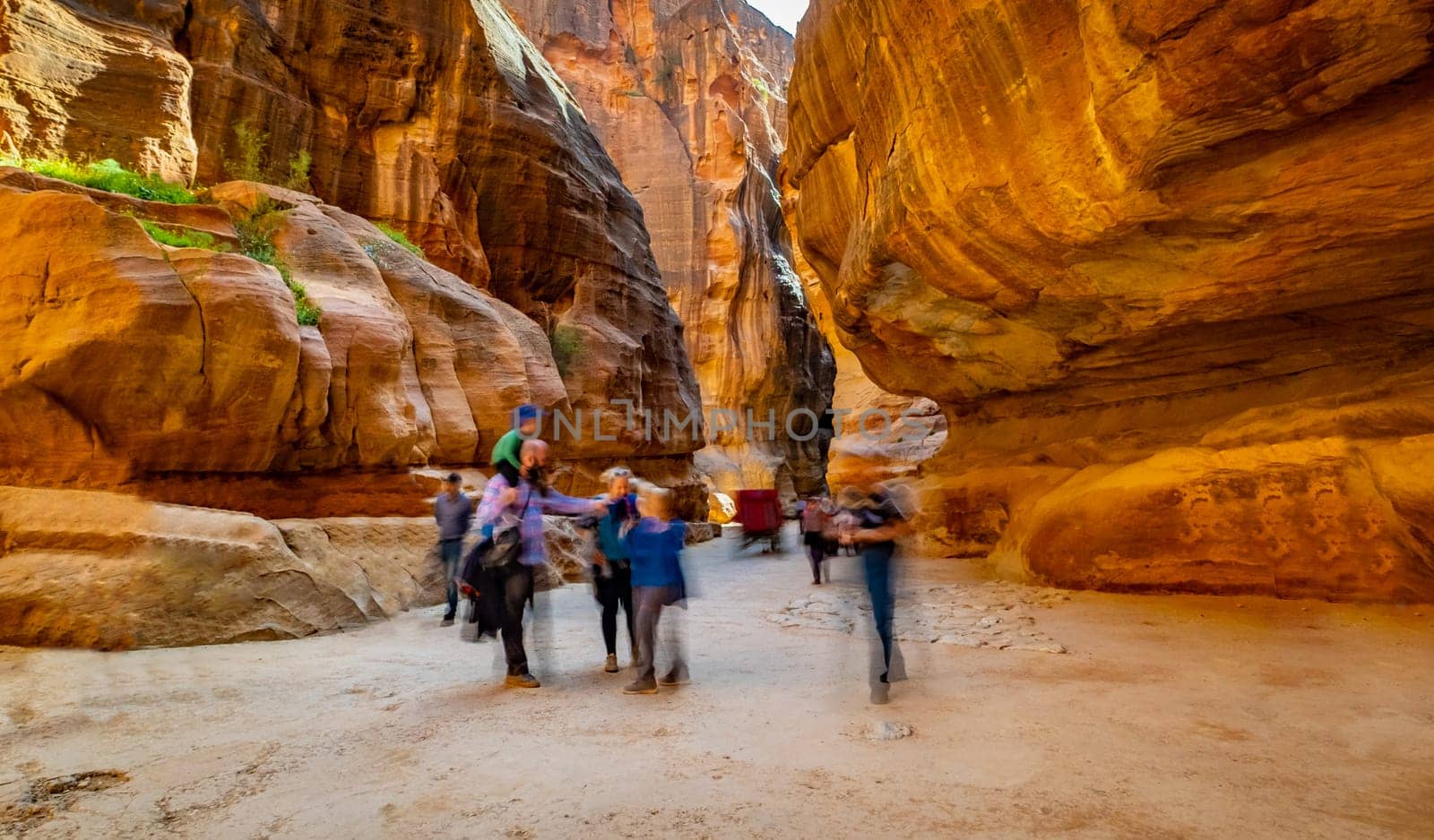 Group of people between sandstone rocks at narrow path in Petra, Jordan