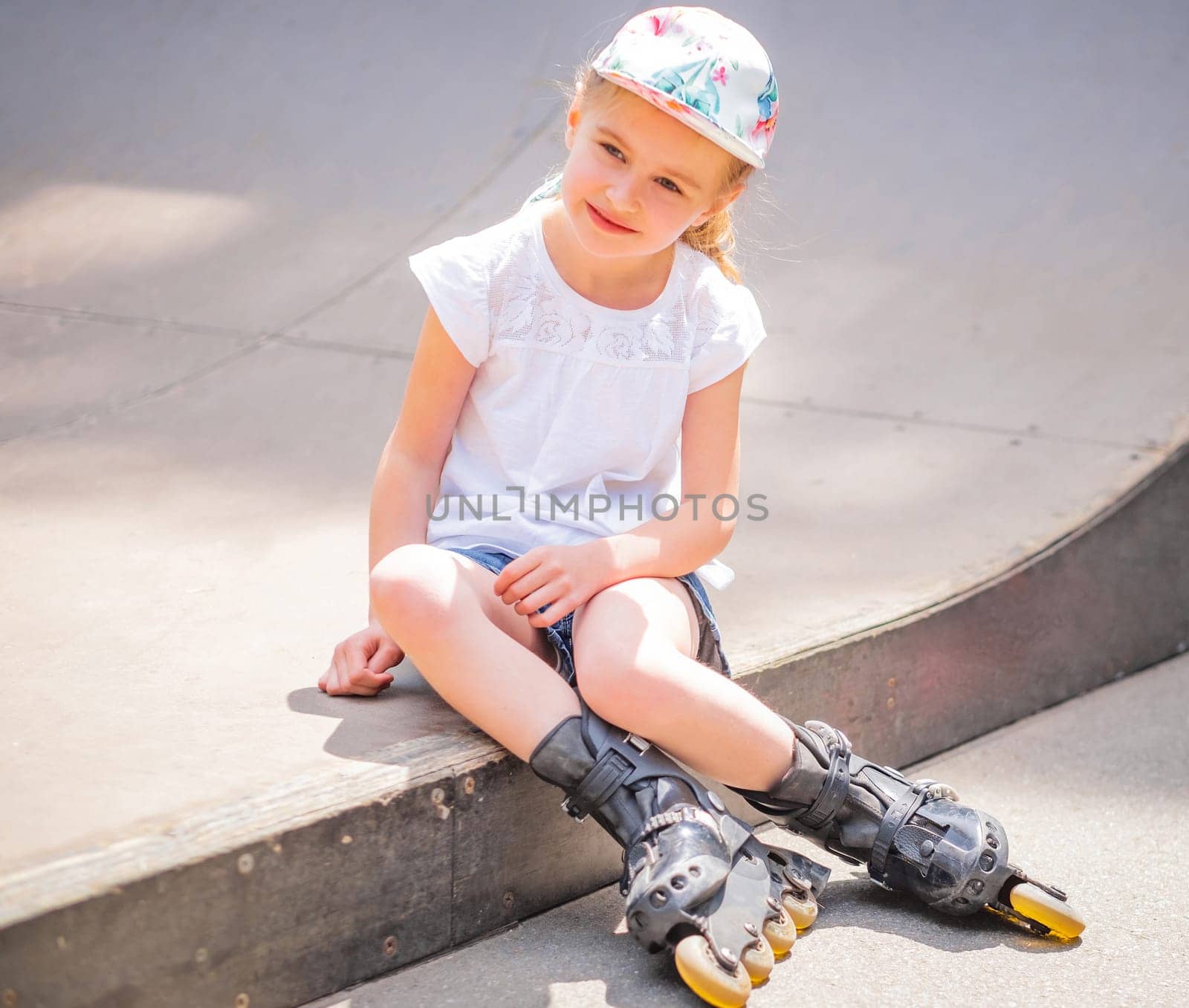 Little girl sitting with roller skates in park