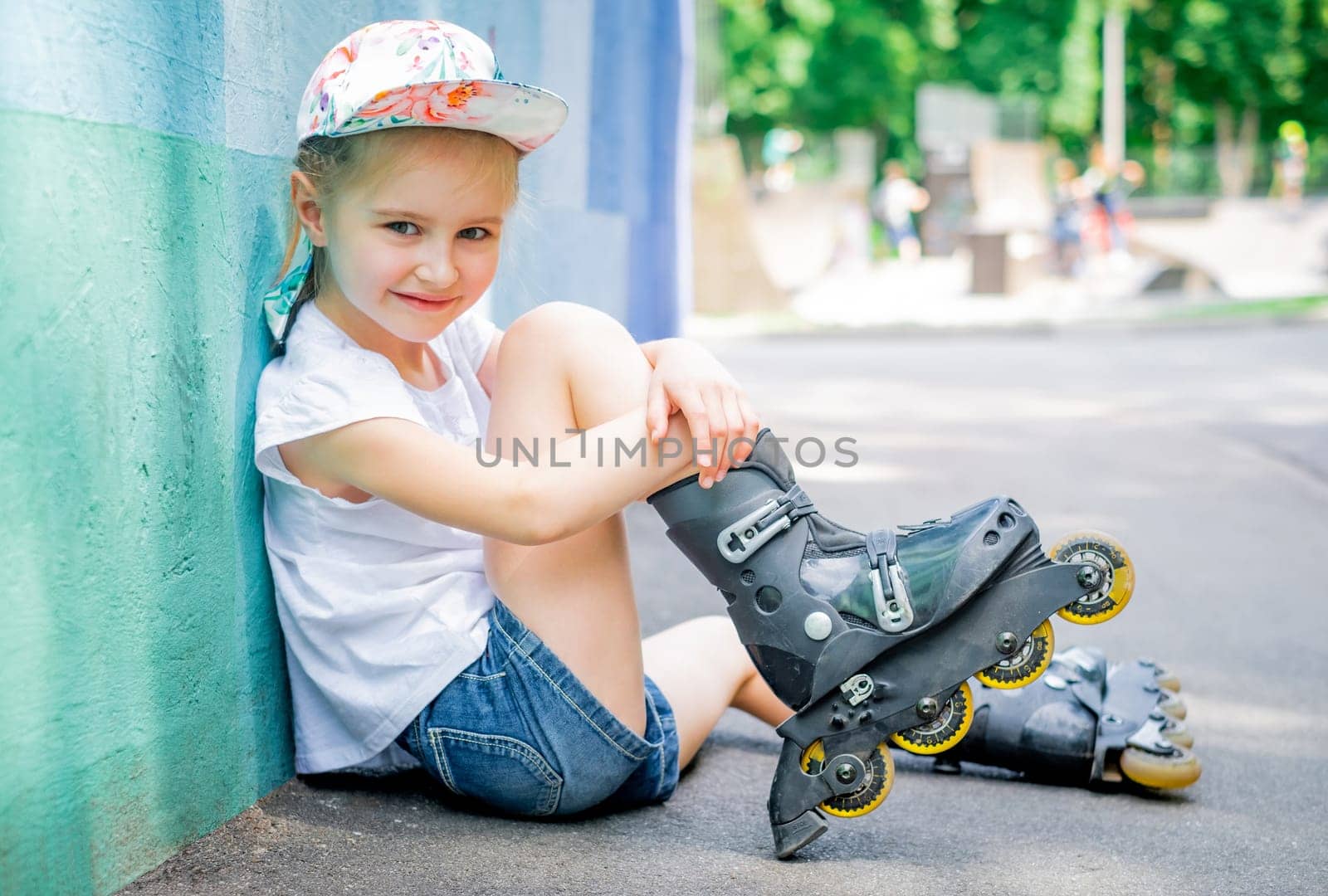 Little girl sitting in roller skates in park