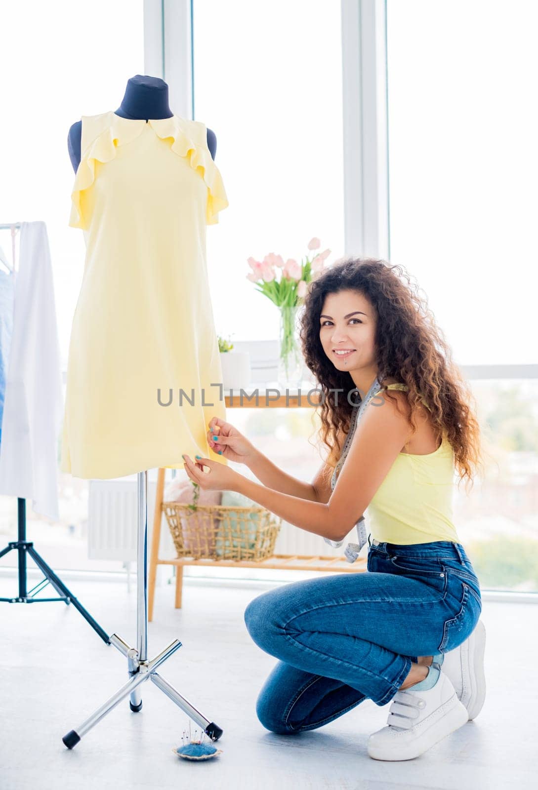 Young seamstress hemming dress on mannequin