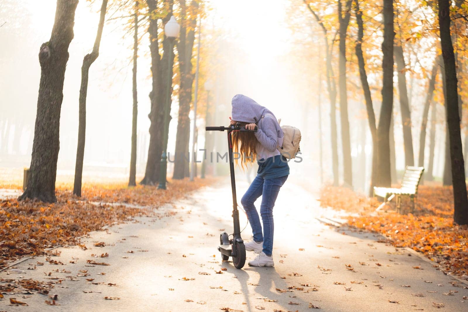 Cute teenage girl on scooter in autumn park