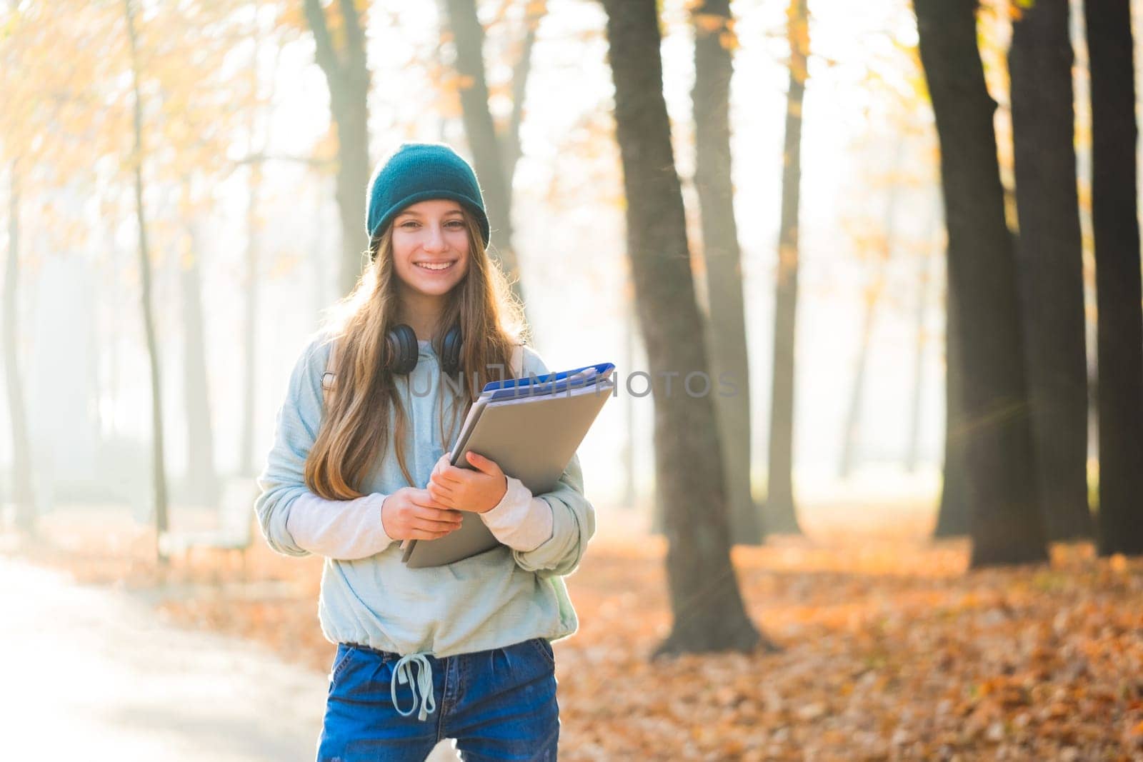 Cute student with books and backpack in autumn park