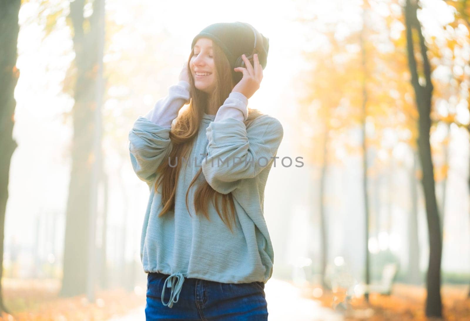 Attractive girl in headphones walking alone park road