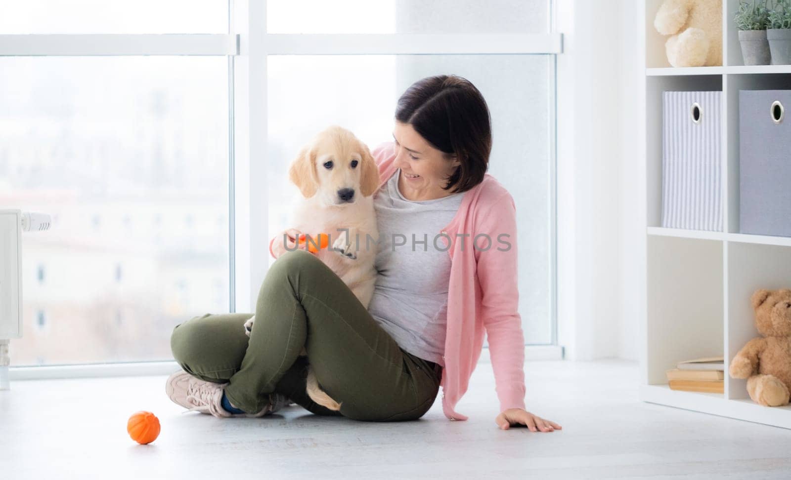 Pretty woman playing with retriever puppy indoors