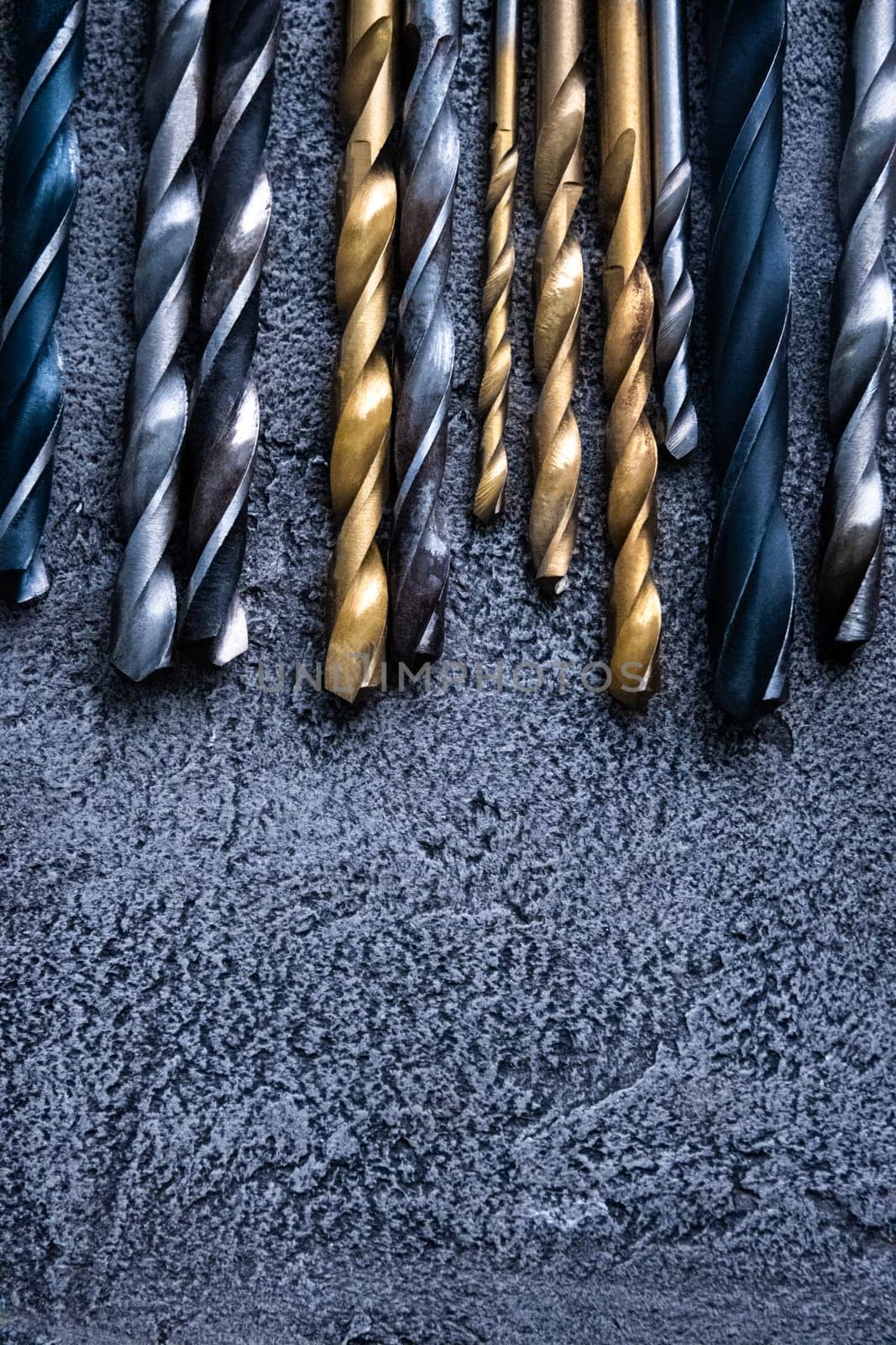 Different sizes drill bits on grey background with copy space