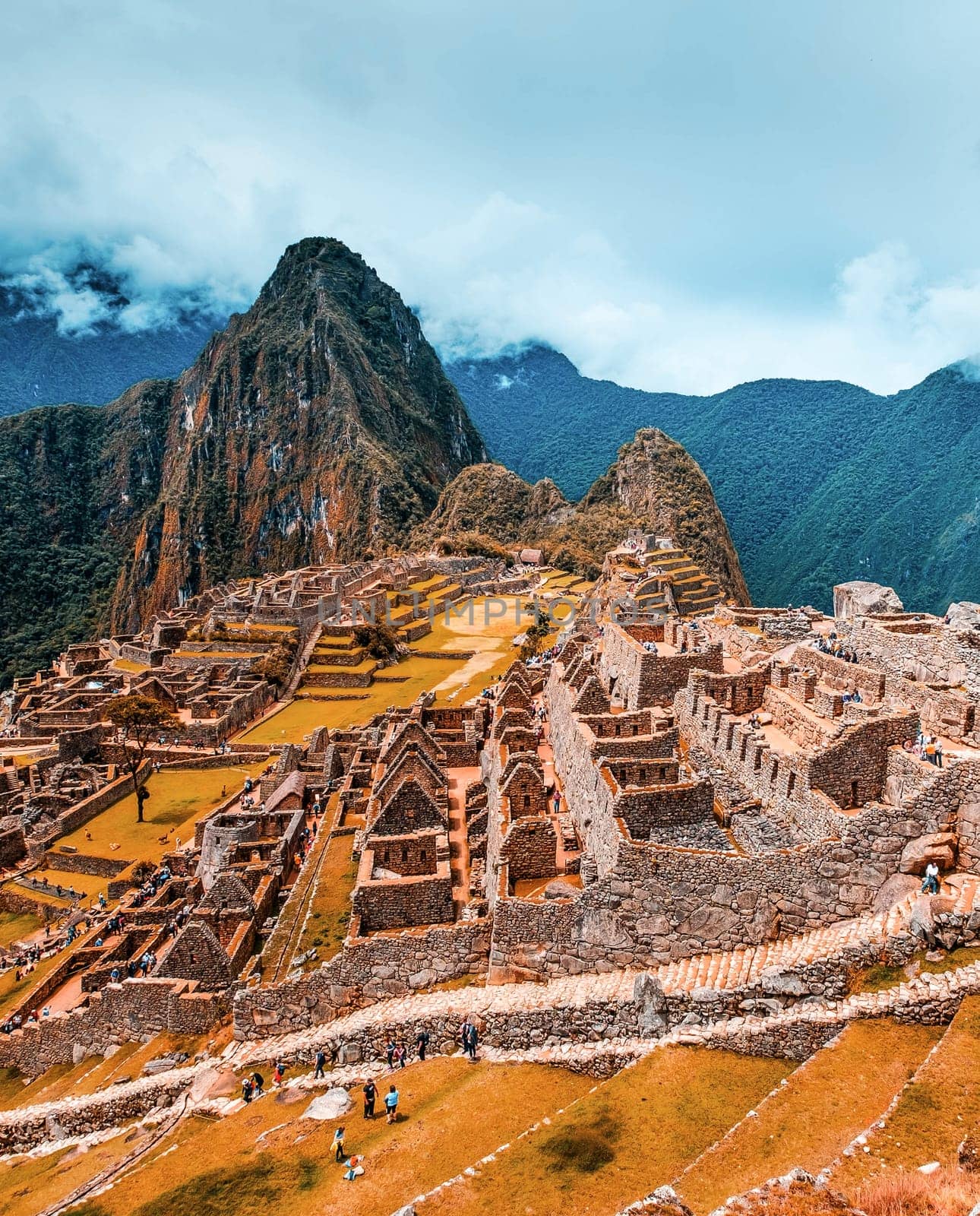 Breathtaking sunshine landscape of ancient majestic Machu Picchu city among high rocky mountains under the clouds