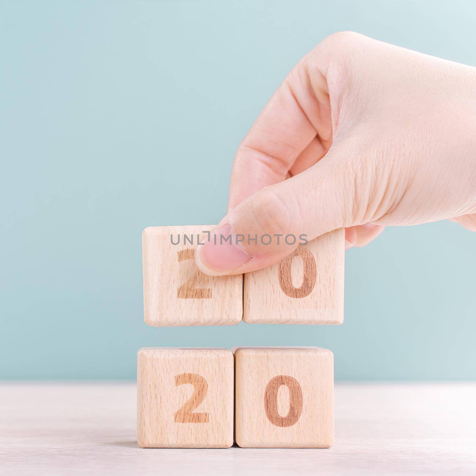 Abstract 2020 & 2019 New year countdown design concept - woman holding wood blocks cubes on wooden table and green background, close up, copy space.