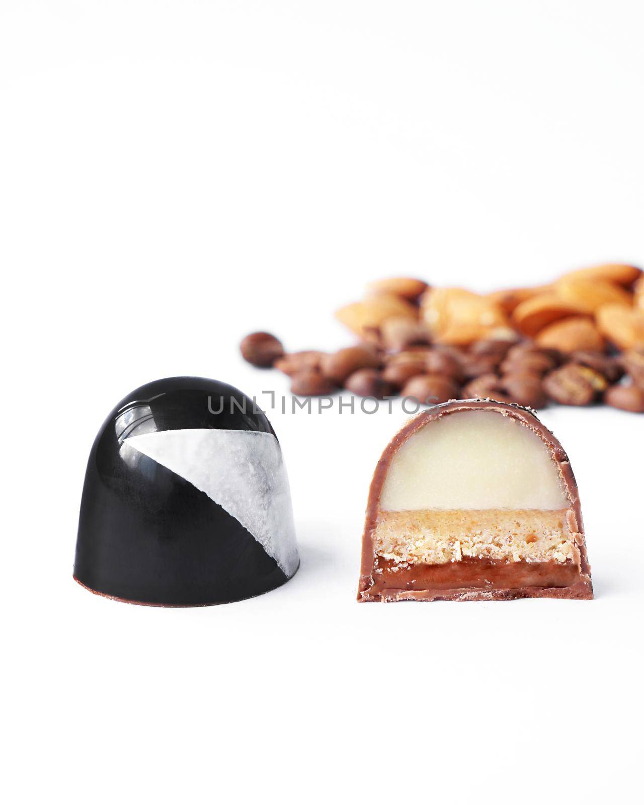 Black chocolate and cutaway candy. Coffee and almond filling. Handmade. Sweets on a white background, vertical photo
