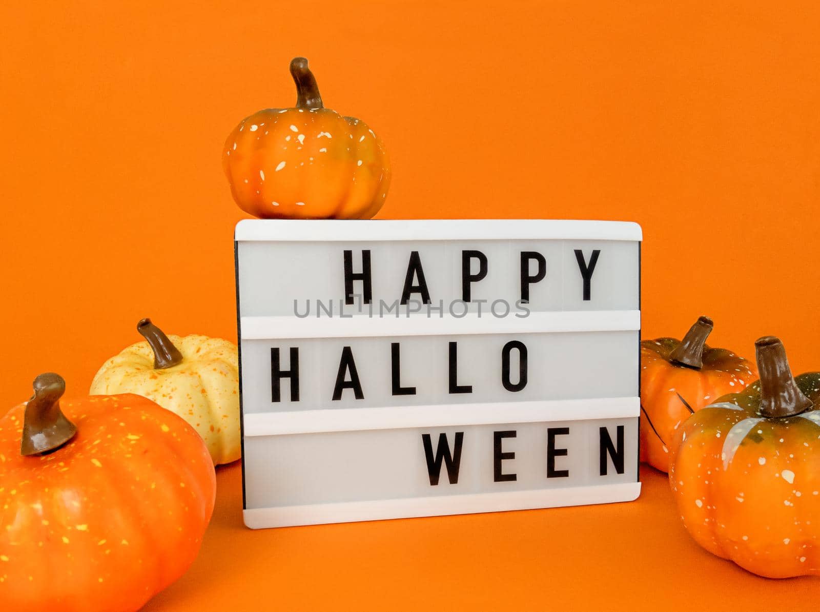Light box with Happy Halloween phrase with pumpkins decoration on an orange background. by anna_artist