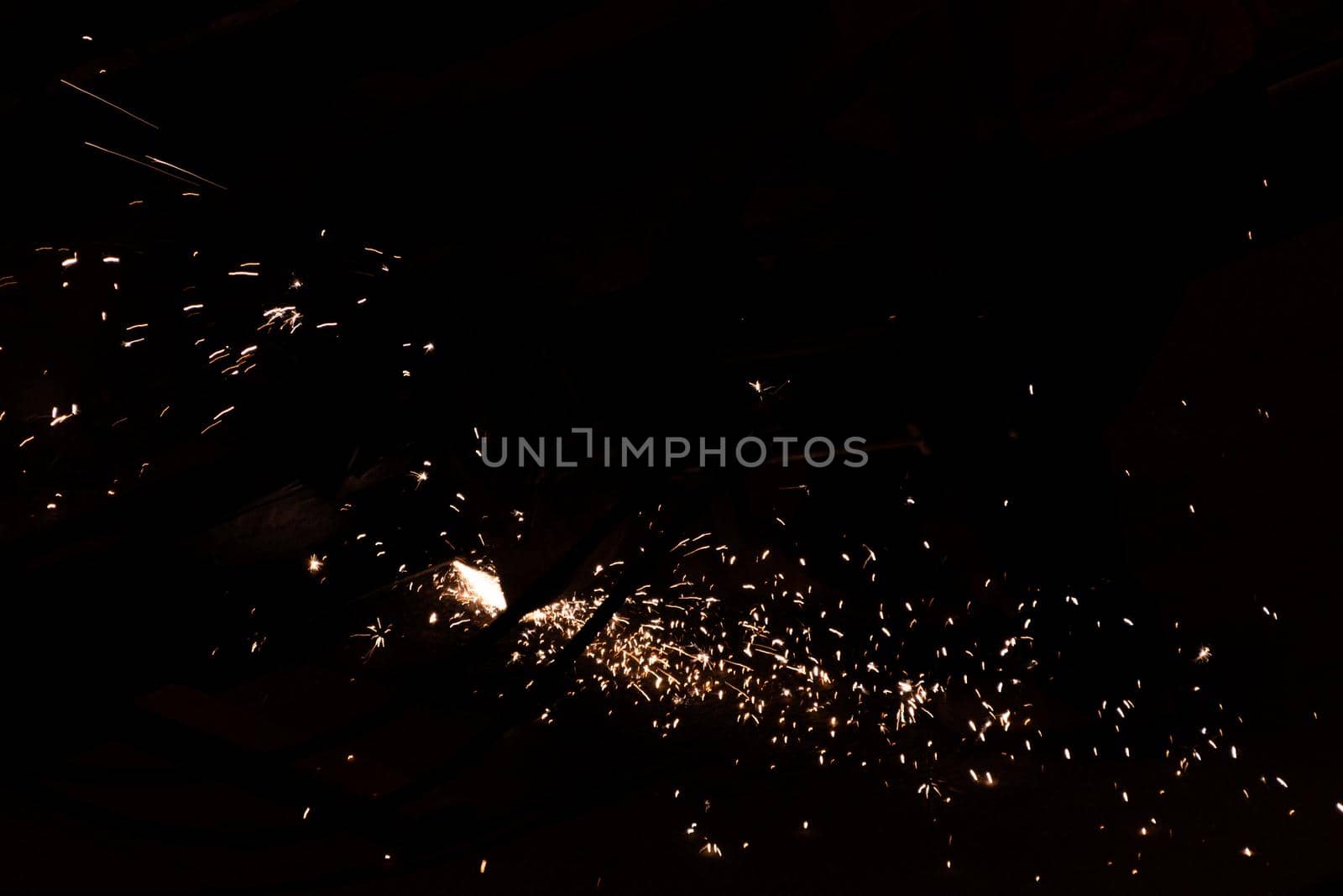 the worker uses a cutting machine to cut metal, focus on flash light line of sharp spark, in low light. High quality photo