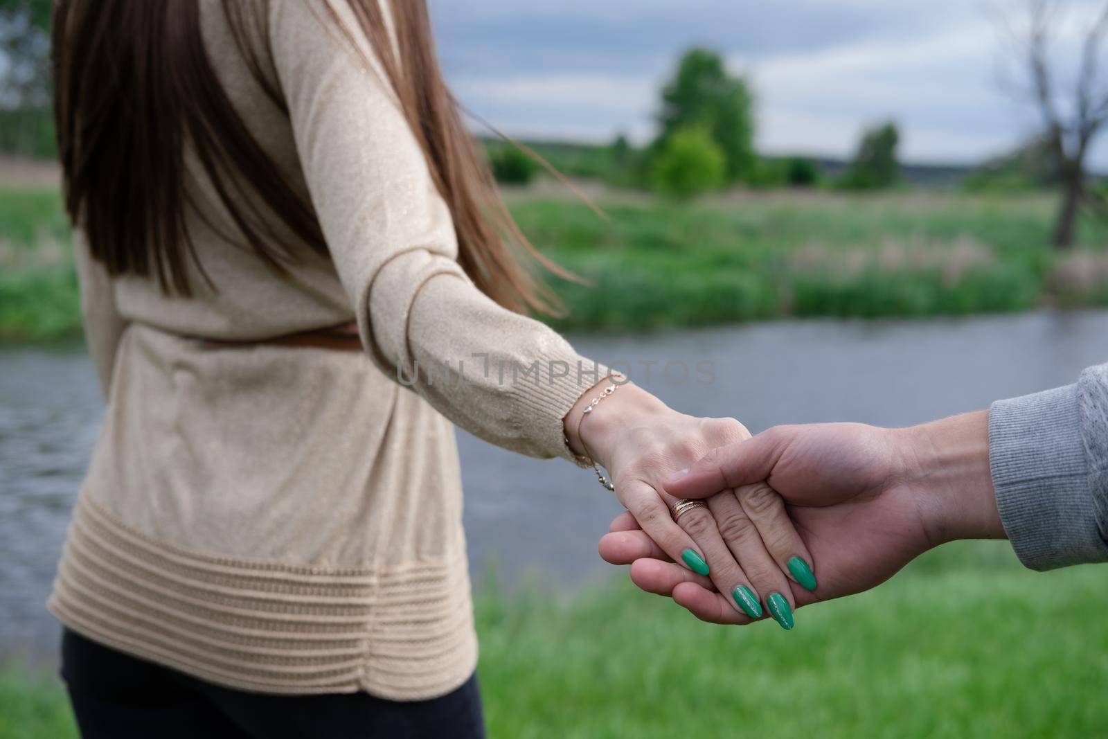 hands of man and woman touch on the background of nature.