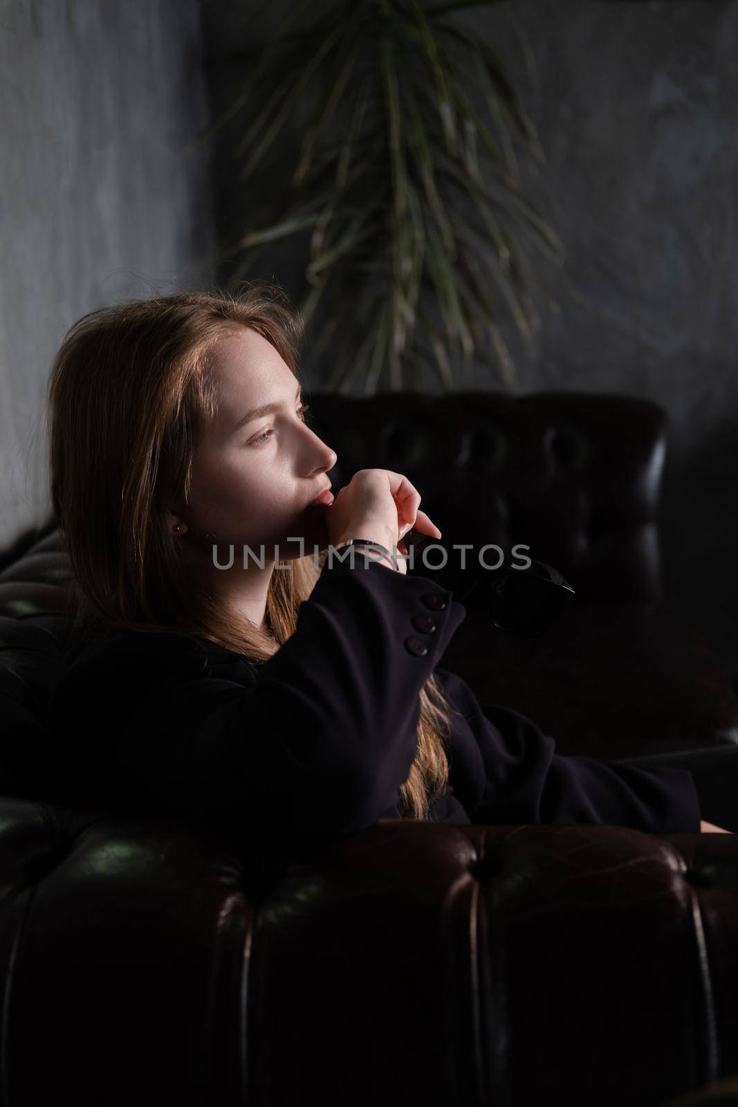 portrait of beautiful confident brunette woman in black in grey dark room. business woman. feminine. millennial people. stylish fashion clothes.