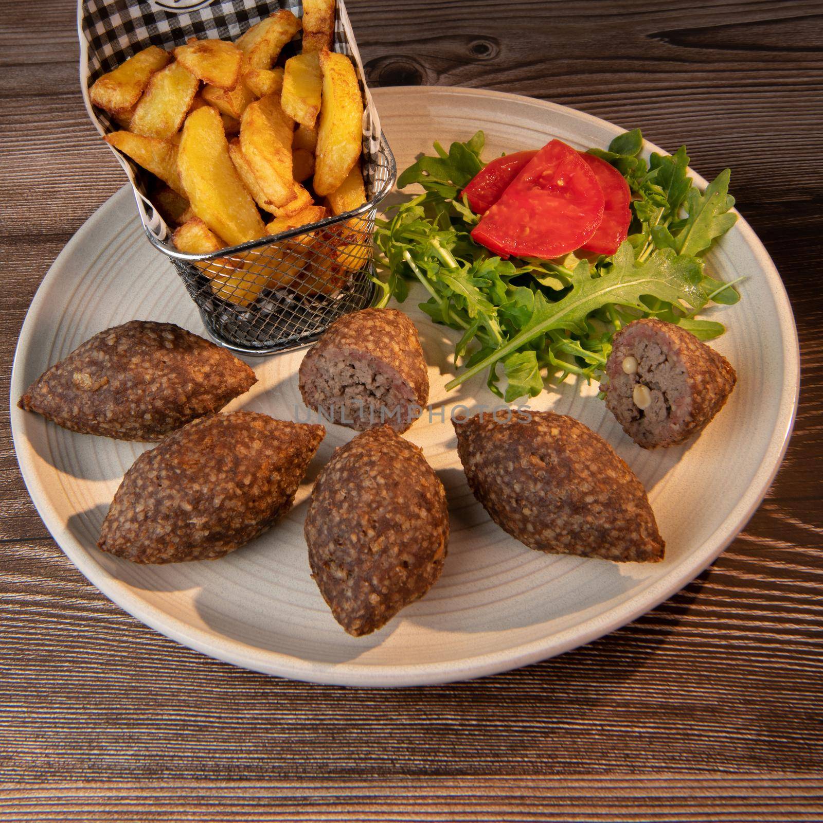 Traditional kebbe and pita bread on big round plate in lebanese restaurant. High quality photo