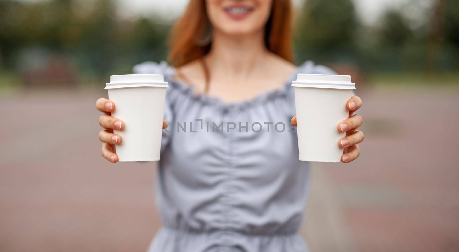 Two white paper cup with coffee in woman hand. Time for drink coffee by AnatoliiFoto