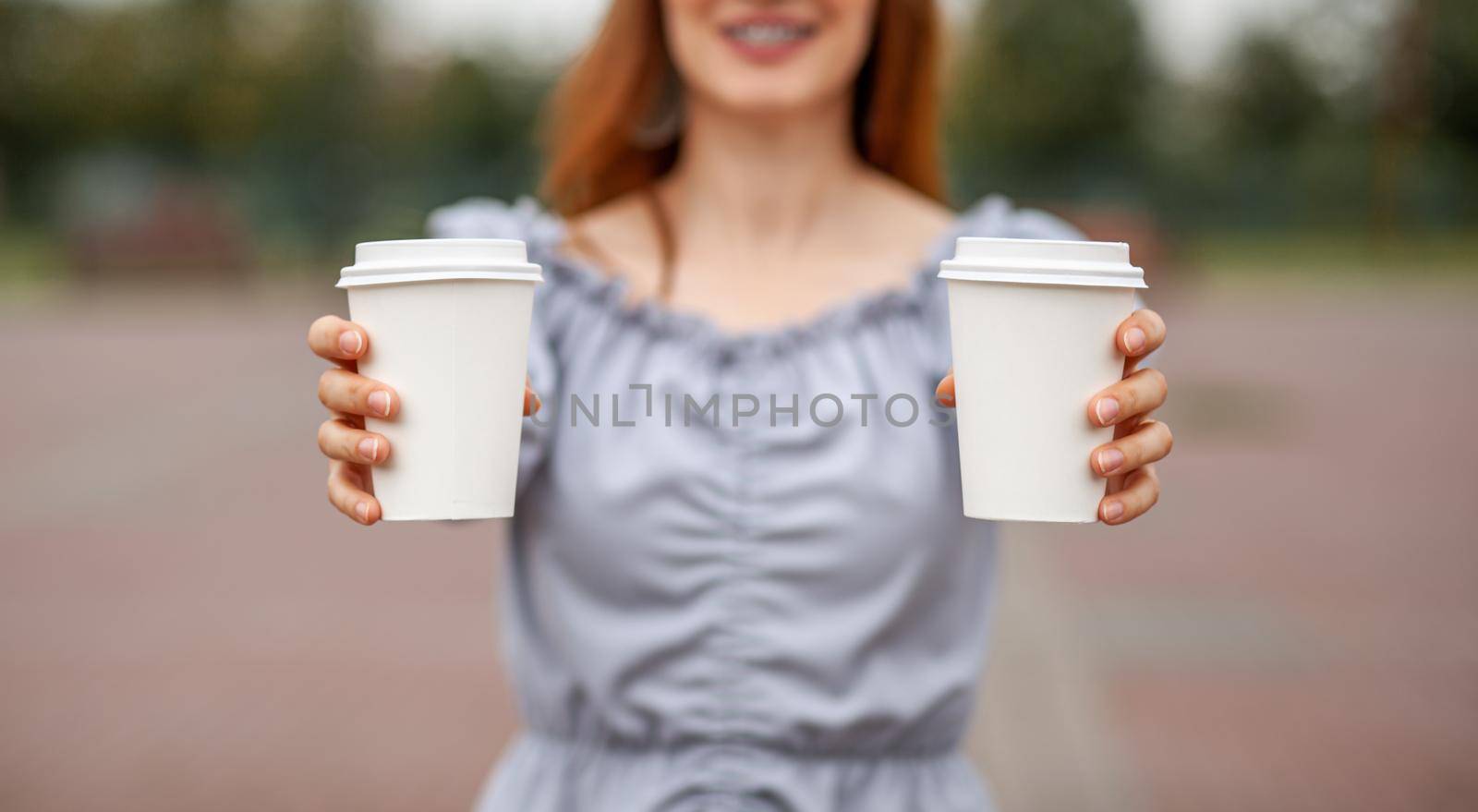 Two white paper cup with coffee in woman hand. Time for drink coffee in city. Coffee to go. Enjoy moment, take a break. Disposable paper cup closeup. Delicious hot beverage. Blank space for text,