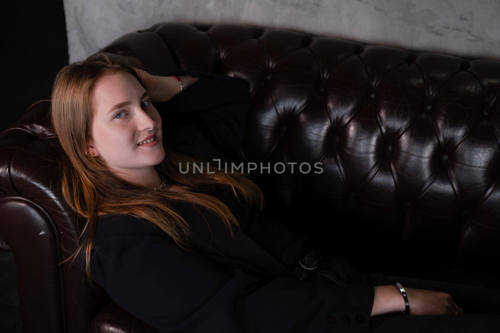 portrait of beautiful confident brunette woman in black in grey dark room. business woman. feminine. millennial people. stylish fashion clothes.