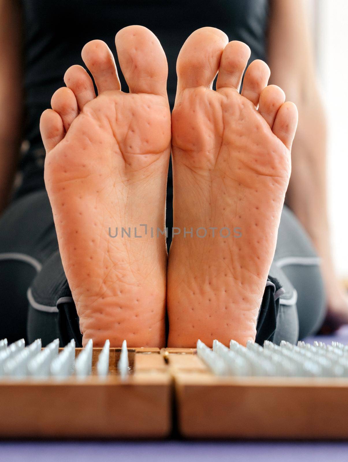 Feet and wooden board with sharp metal nails. Sadhu foot board. Yoga relaxation practice training by Mariakray