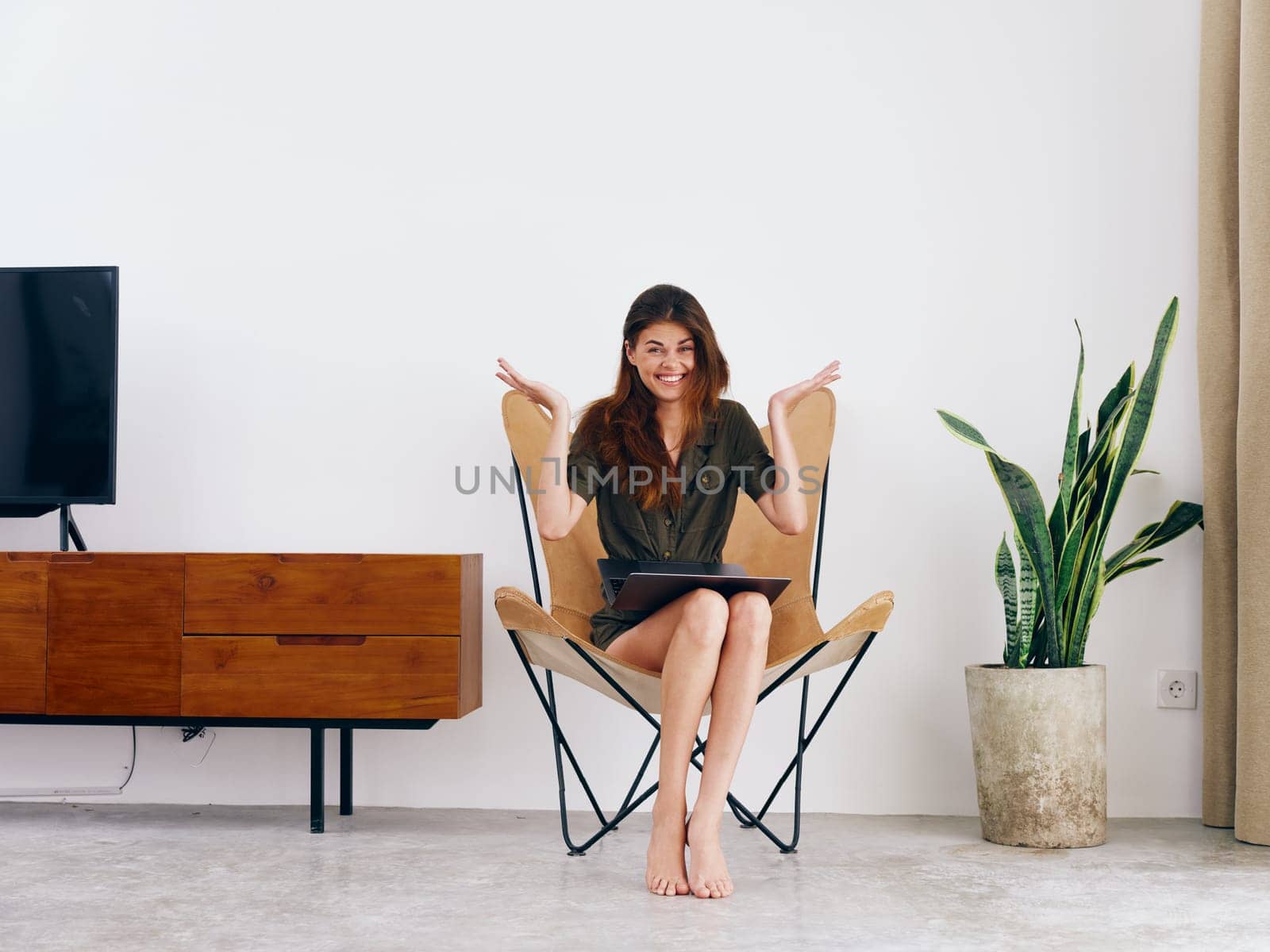 Woman student study sits on a chair with a laptop work at home smile, modern stylish interior Scandinavian lifestyle, copy space. High quality photo