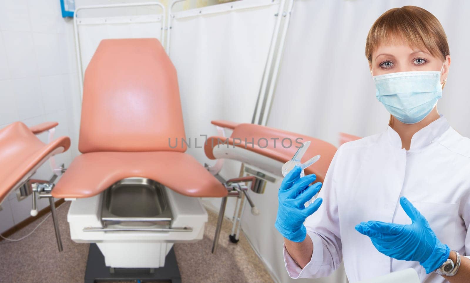 Female gynecologist in protective mask and whitecoat with gynecological vaginal retractor in hand in medical room