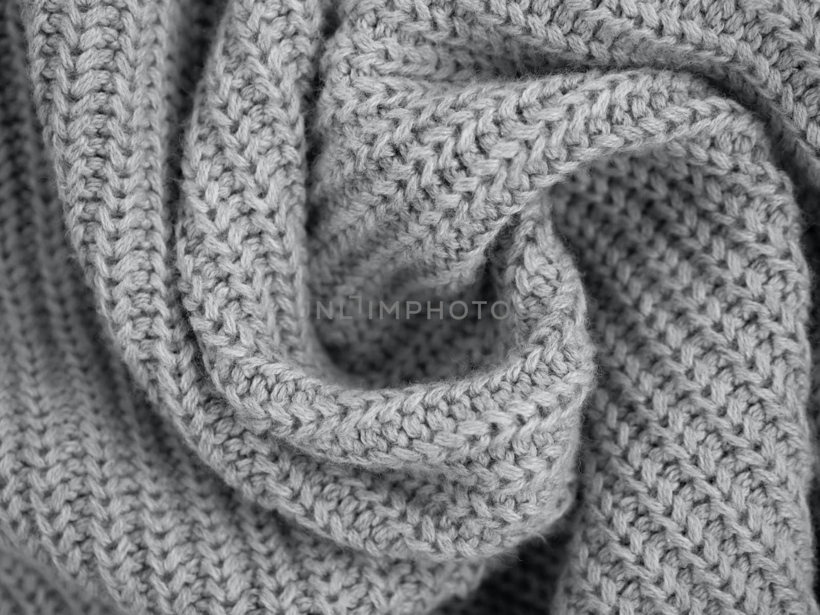 Wavy folds material. Knitted warm ultimate gray sweater or scarf. Cozy composition in the home atrosphere. Trendy grey wool fabric texture close up background. Comfortable style cloth. Soft focus
