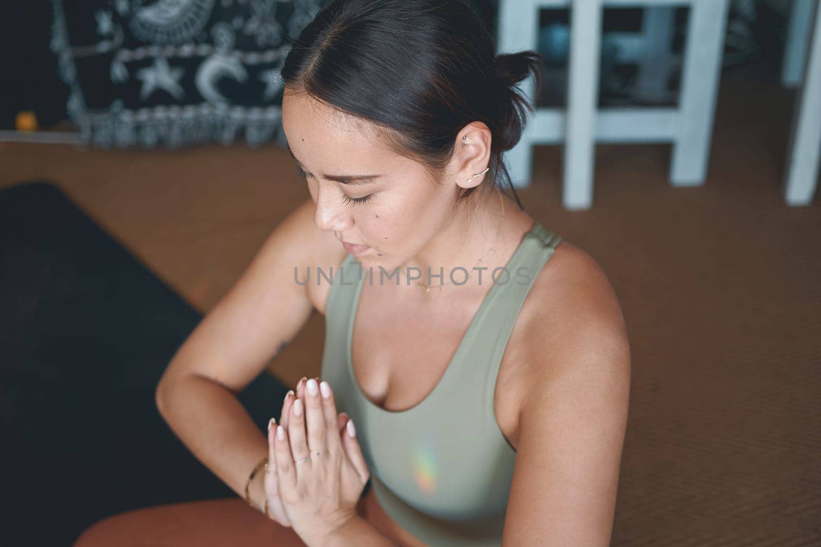 Yoga teaches us to be kinder to ourselves. a young woman meditating while practising yoga at home