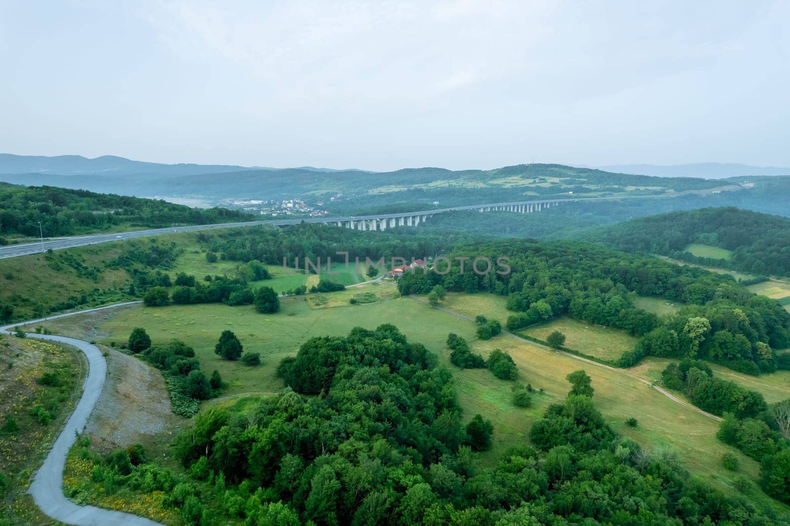 Aerial view of bridge showcases breathtaking landscape of mountains and lush green forests.