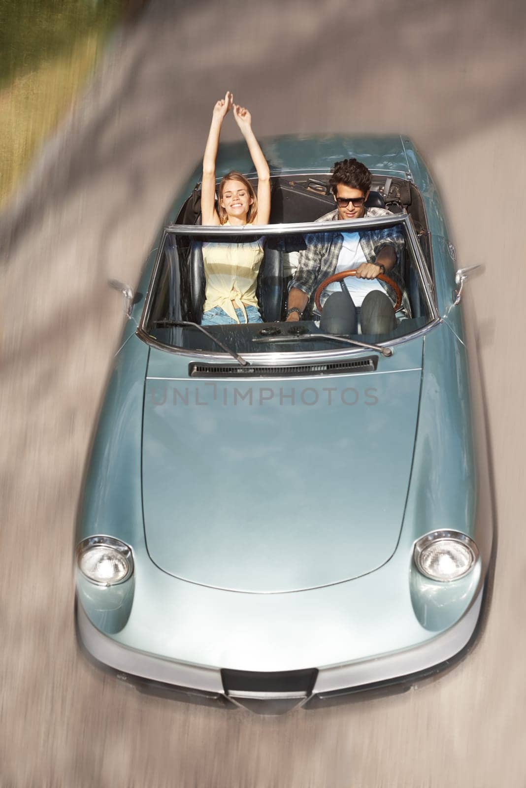 Feeling the rushing air. High angle shot of a young woman with her arms raised while riding in a convertible with her boyfriend