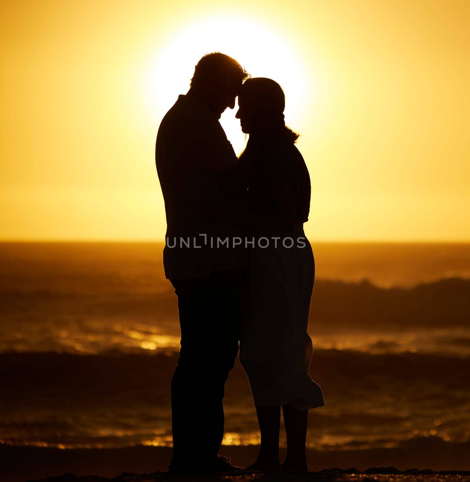 Silhouette, couple and love on a beach at sunset for vacation or holiday outdoor. Romantic man and woman hug in nature with creative sky, space and ocean for care, shadow art and travel or freedom.