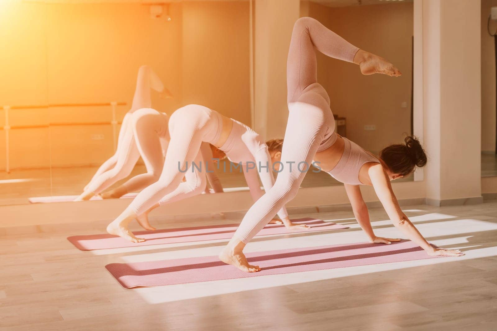 Young woman with long hair in white swimsuit and boho style braclets practicing outdoors on yoga mat by the sea on a sunset. Women's yoga fitness routine. Healthy lifestyle, harmony and meditation