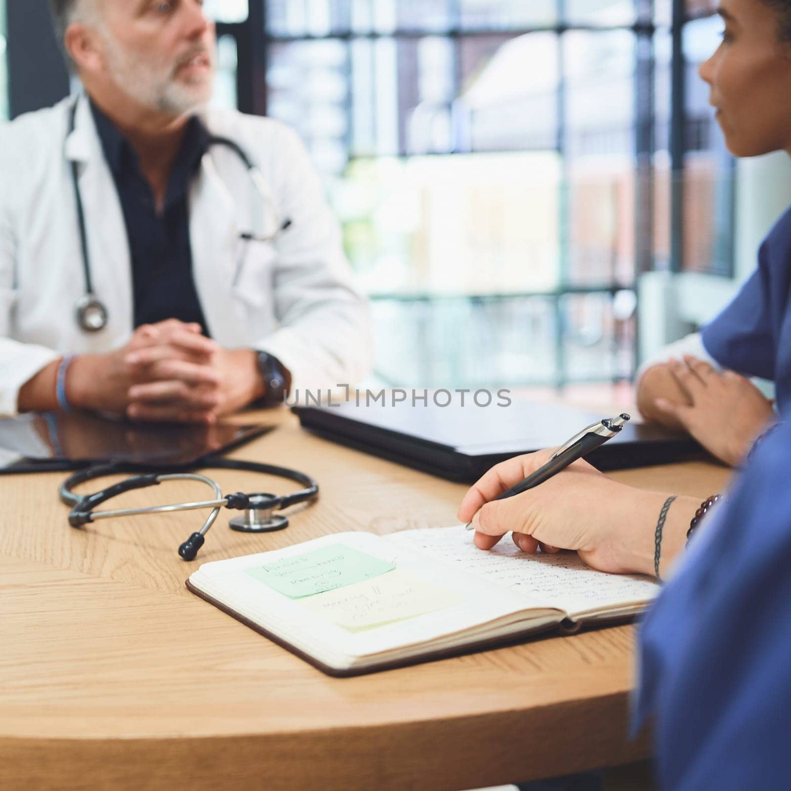 Taking note of important info. Closeup shot of a doctor writing notes during a meeting with colleagues in a hospital. by YuriArcurs