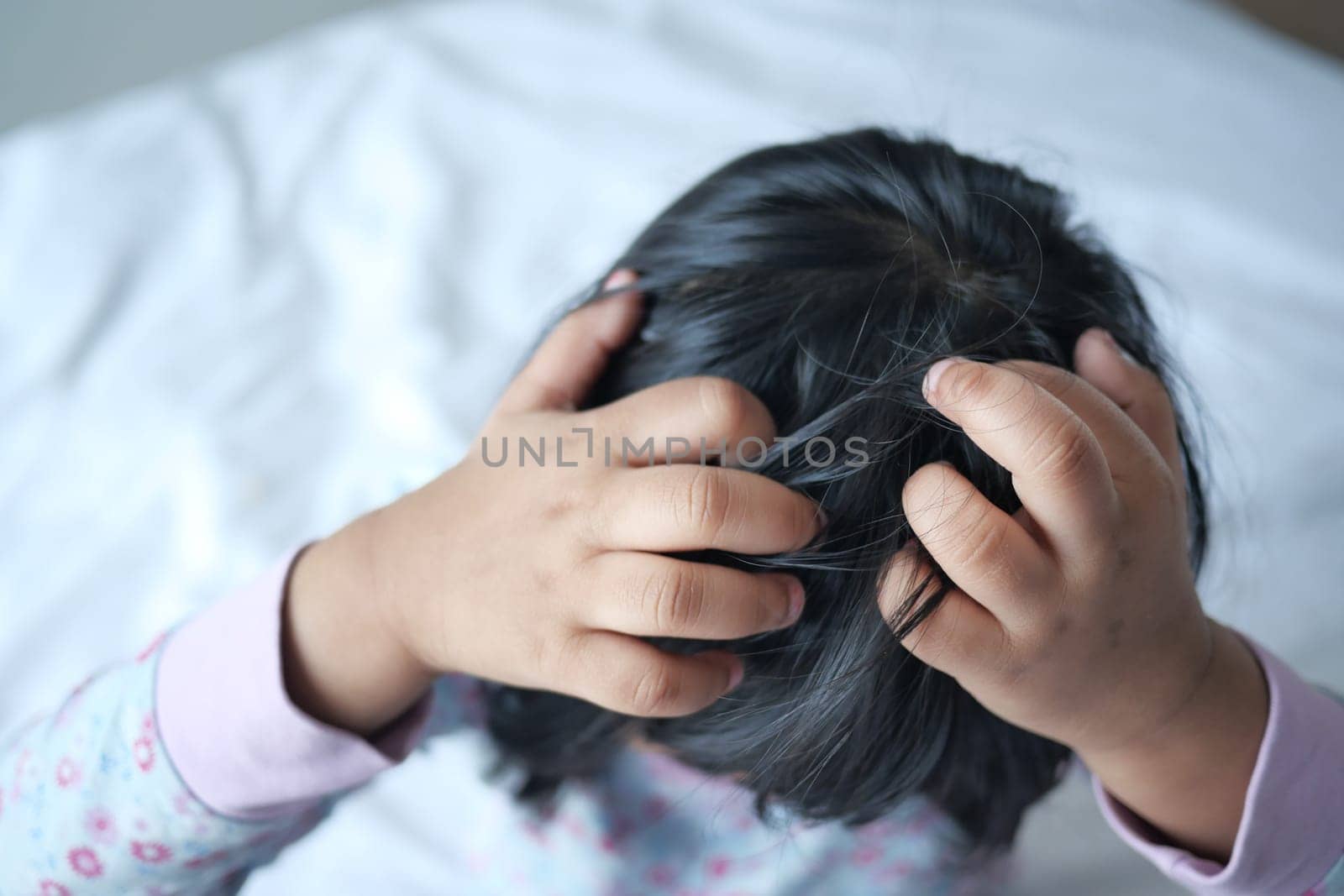 child scratching head sitting on the bed Annoying itch