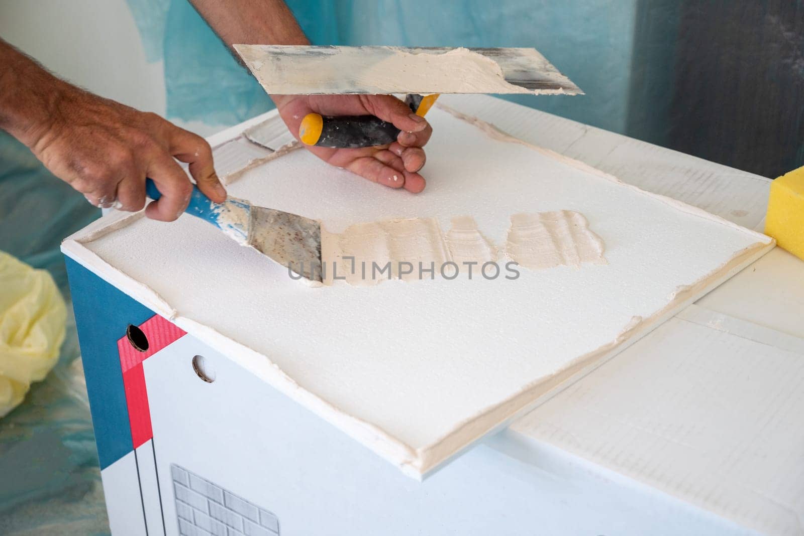 adhesive plaster application of styrofoam ceiling tiles of a home kitchen