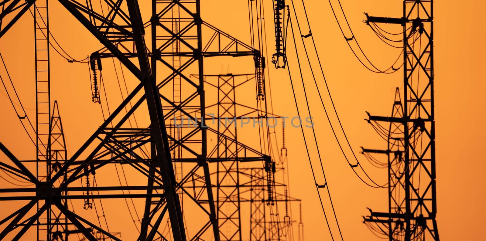 High voltage electric transmission tower. High voltage power lines on electric pylon against a sunset sky. Electrical infrastructure. Energy crisis. Electric power distribution. Energy distribution. by Fahroni