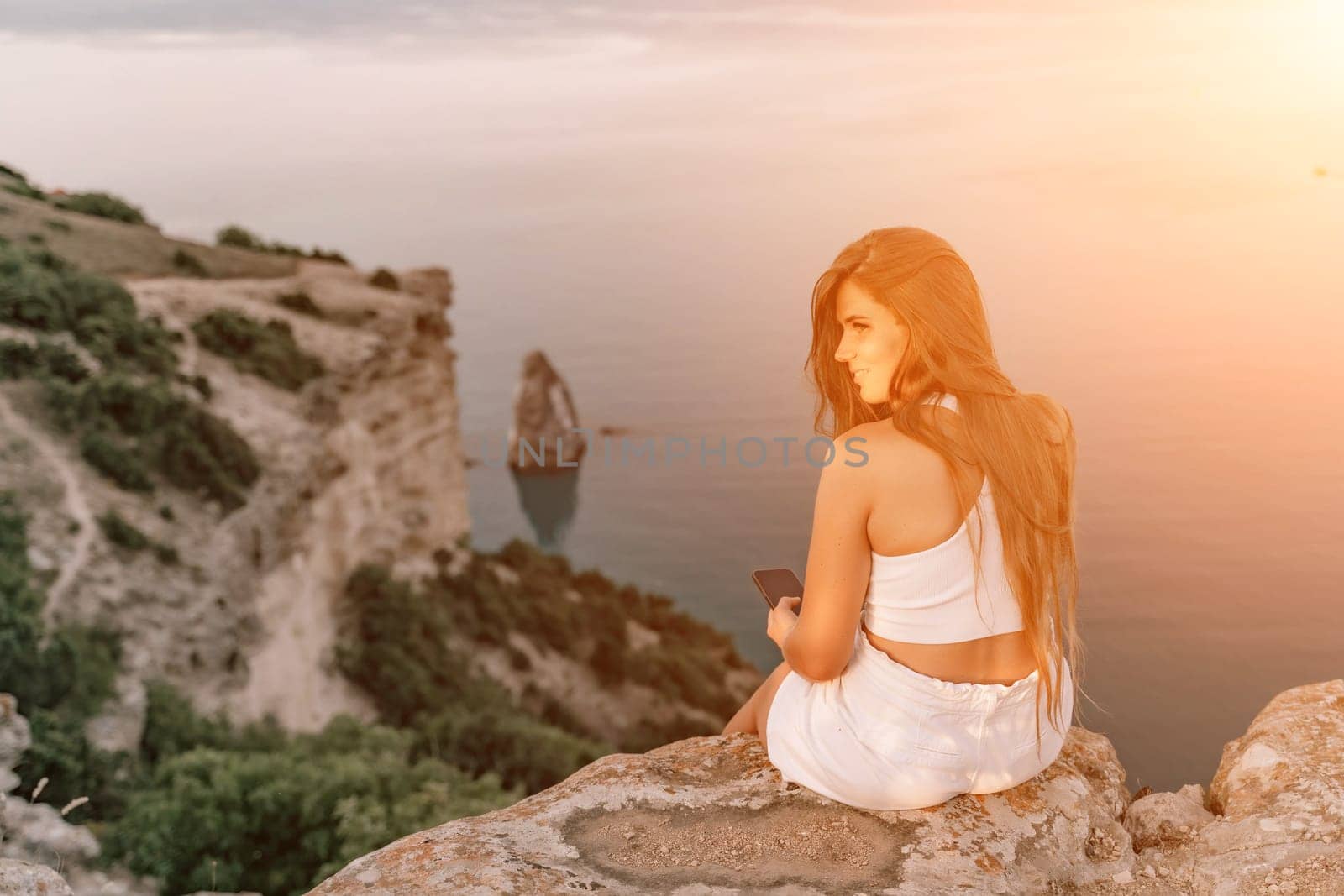 A portrait of a woman in white shorts and T-shirt with long hair, standing against the sea, showcasing her joyful and contented mood