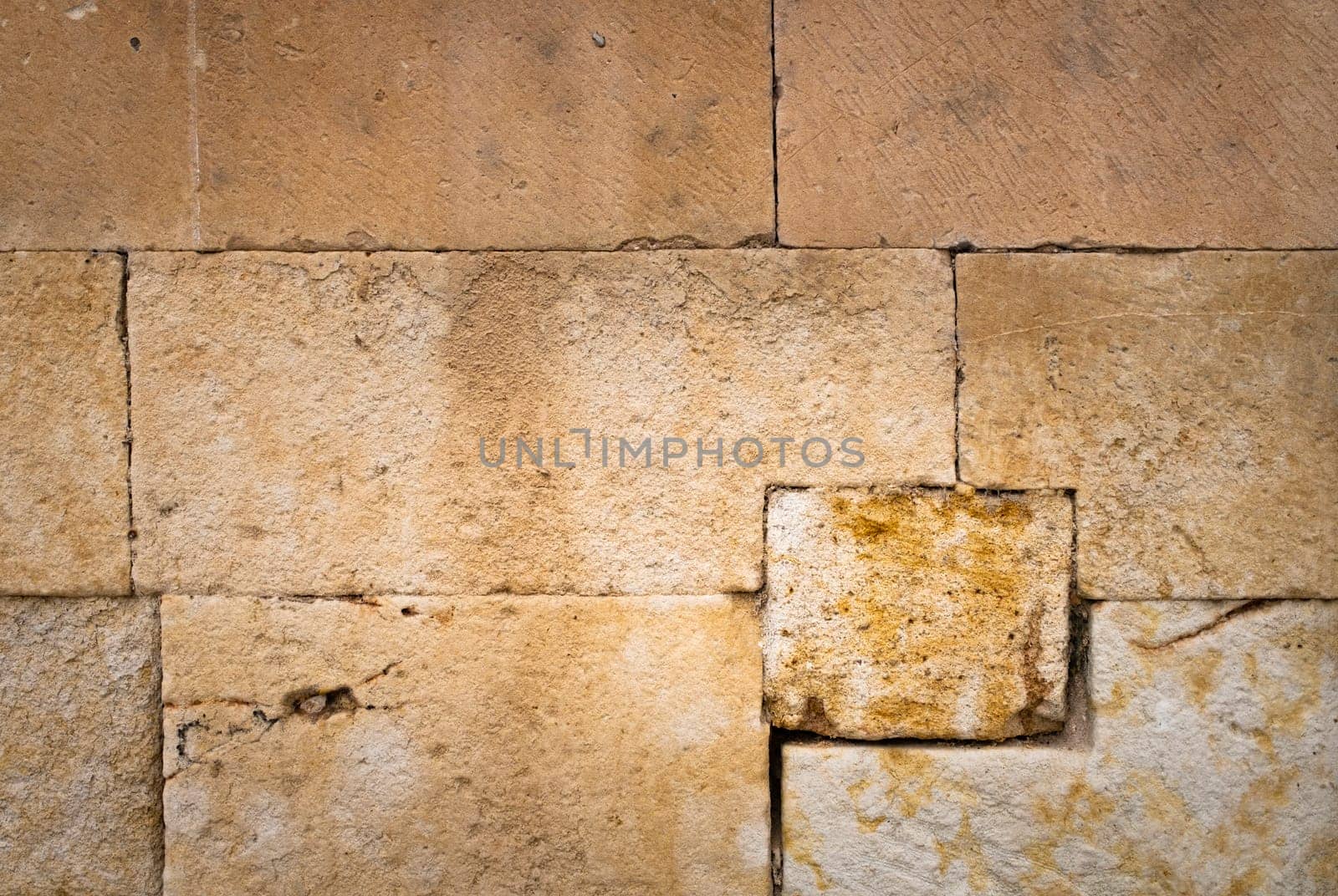 Large stone wall of an old building, with a lot of texture and warm tones, to be used as a stencil or as a background.