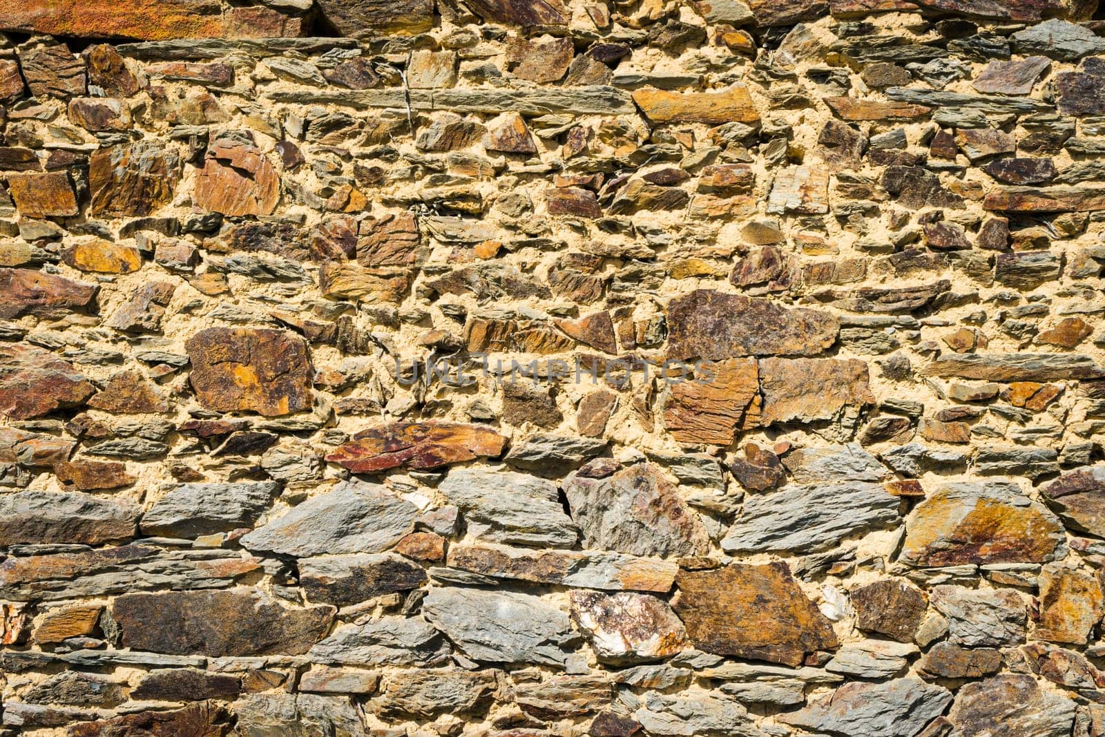 View of old wall built with stones in warm tones. Concept for backgrounds and textures.