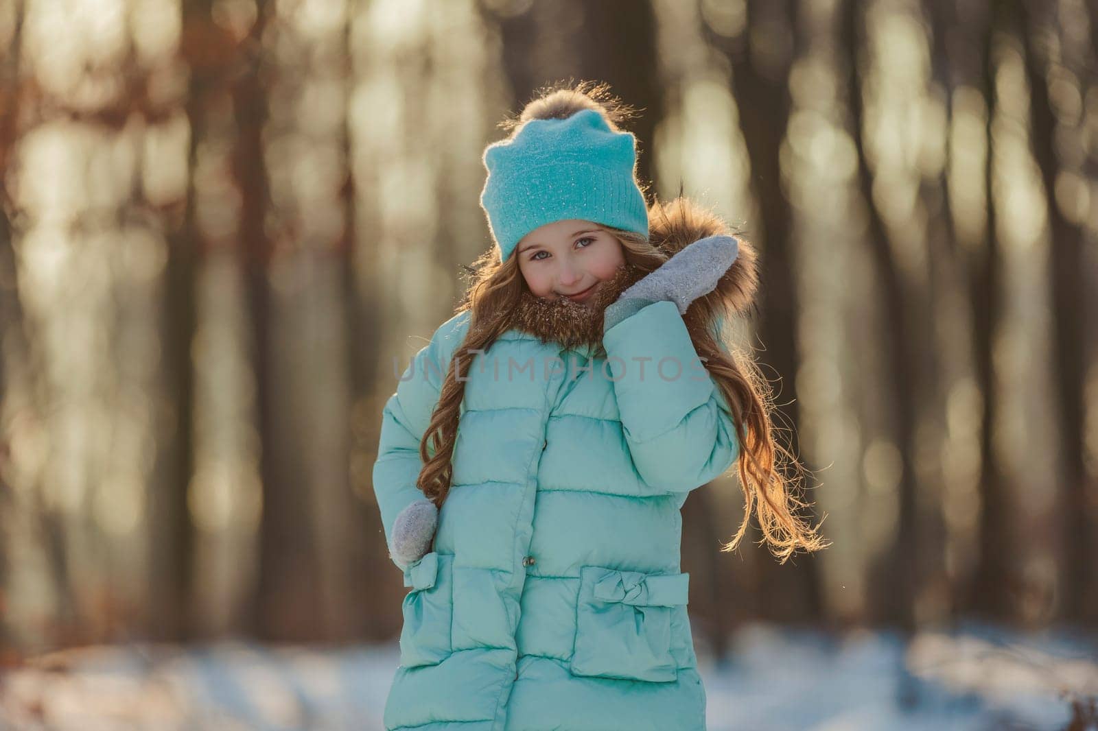 portrait of a girl against the backdrop of a winter forest illuminated by the sun