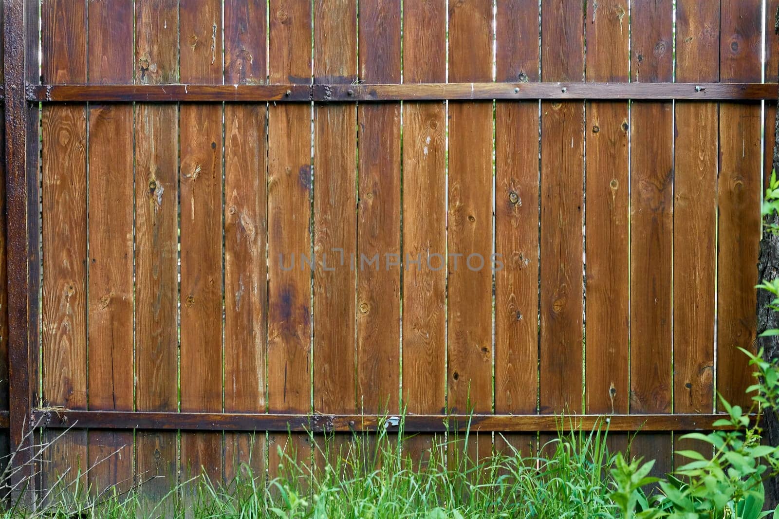 a barrier, railing, or other upright structure, typically of wood or wire, enclosing an area of ground
