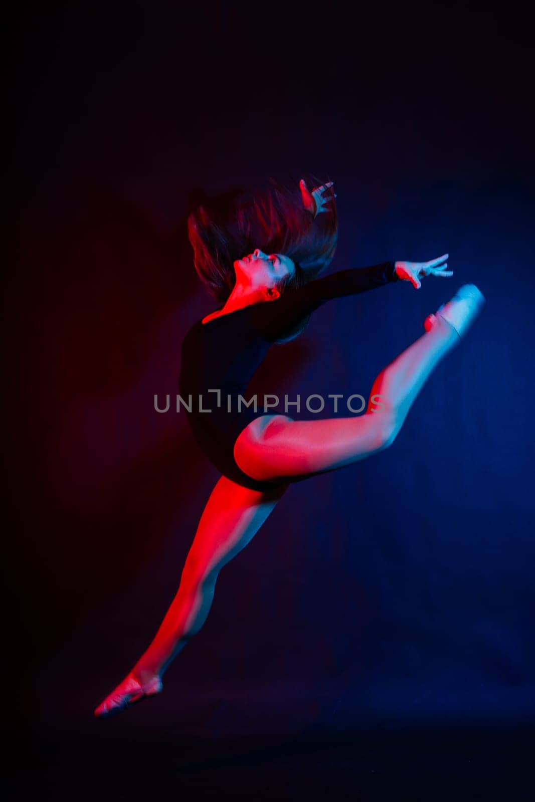 Full length teen girl smiling doing fitness exercises, isolated on a white and dark background