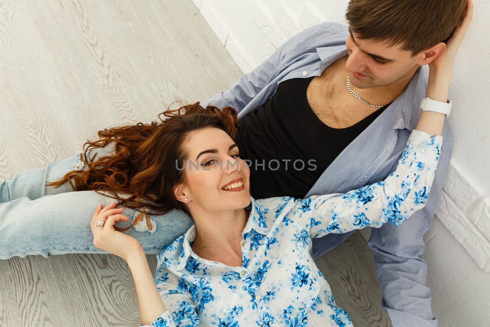 Dreamy couple lying on floor in empty room and looking up, imagine future interior design project, white background