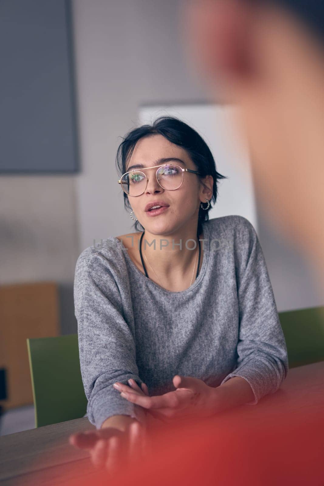 In a modern office, a young smile businesswoman with glasses confidently explains and presents various business ideas to her colleagues, showcasing her professionalism and expertise
