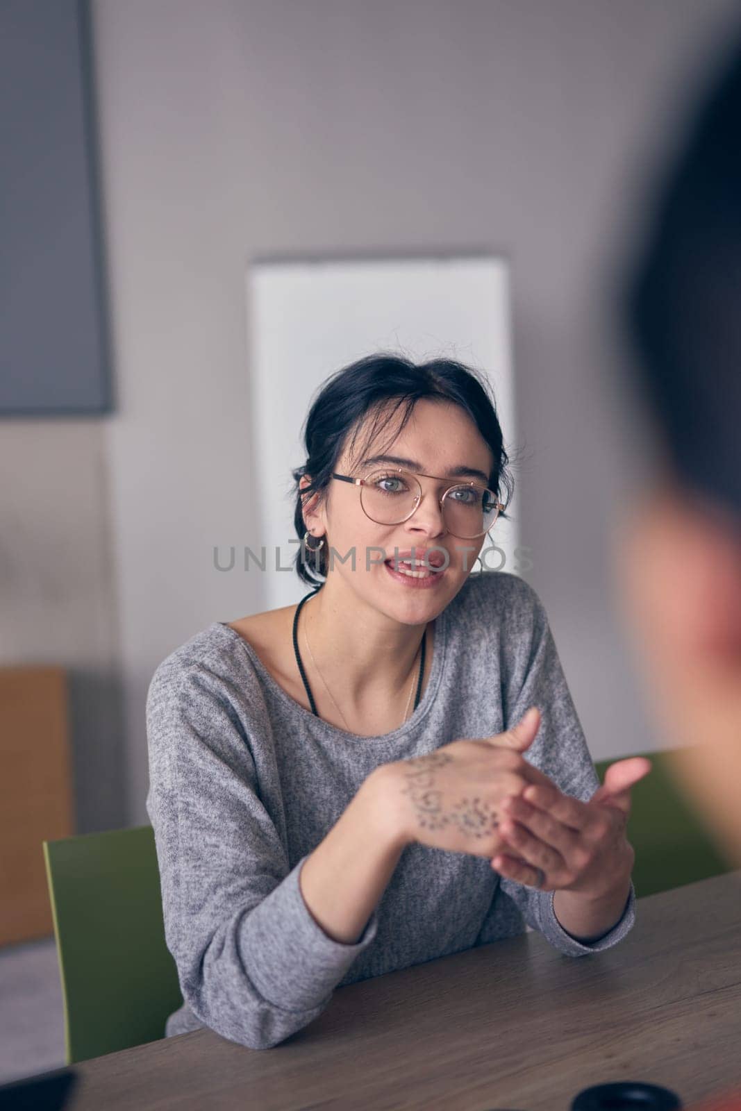 In a modern office, a young smile businesswoman with glasses confidently explains and presents various business ideas to her colleagues, showcasing her professionalism and expertise. by dotshock